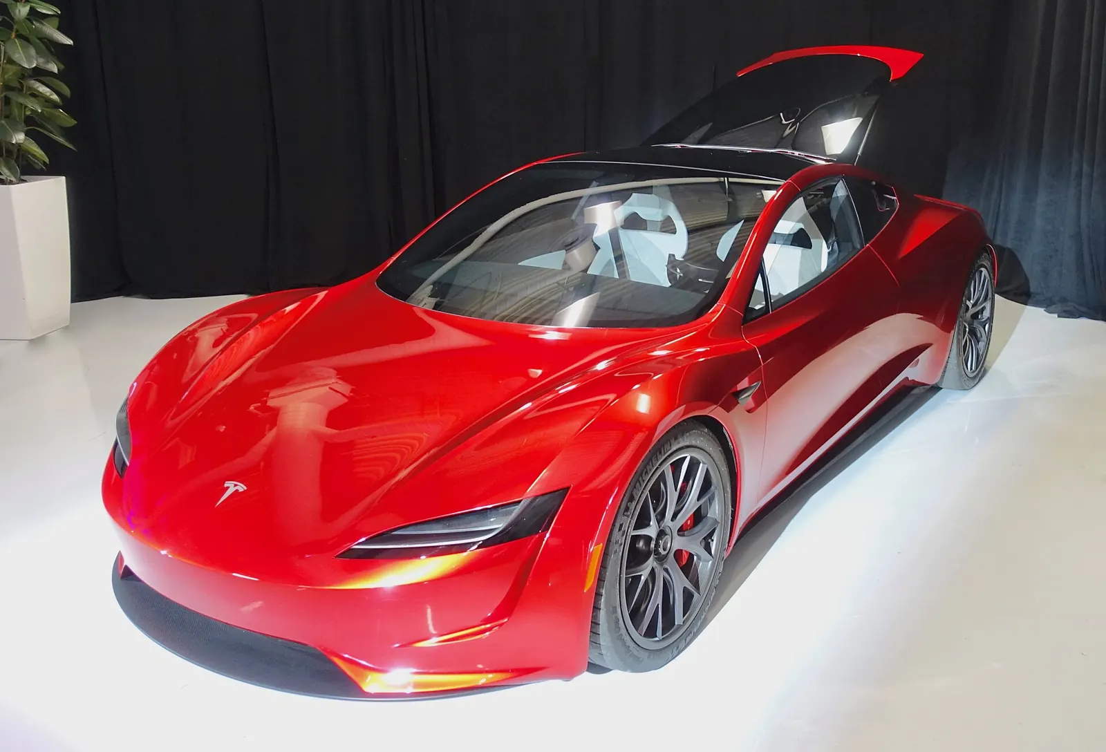Red second-generation Tesla Roadster prototype on display, seen from the front three-quarter angle with its glass roof panel stowed