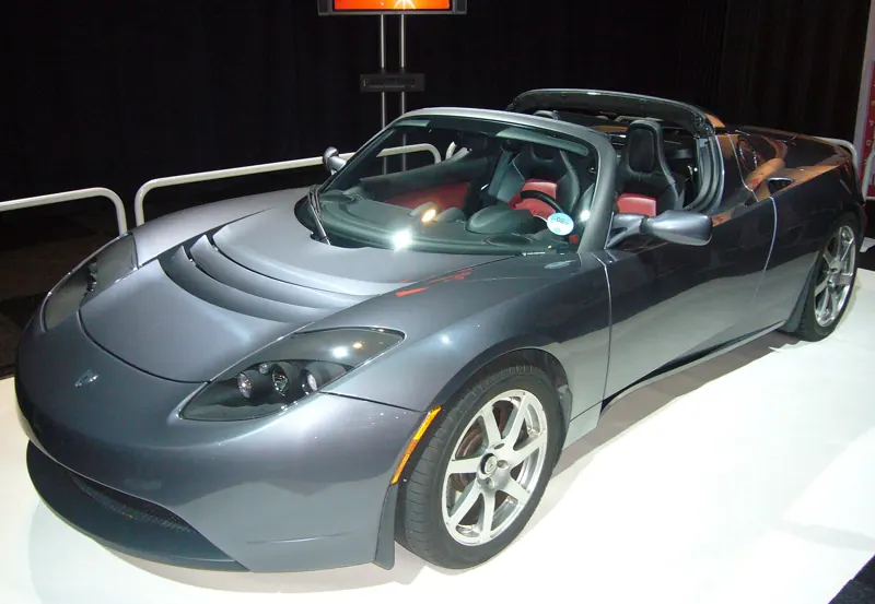 Dark grey first-generation Tesla Roadster convertible on a display stand