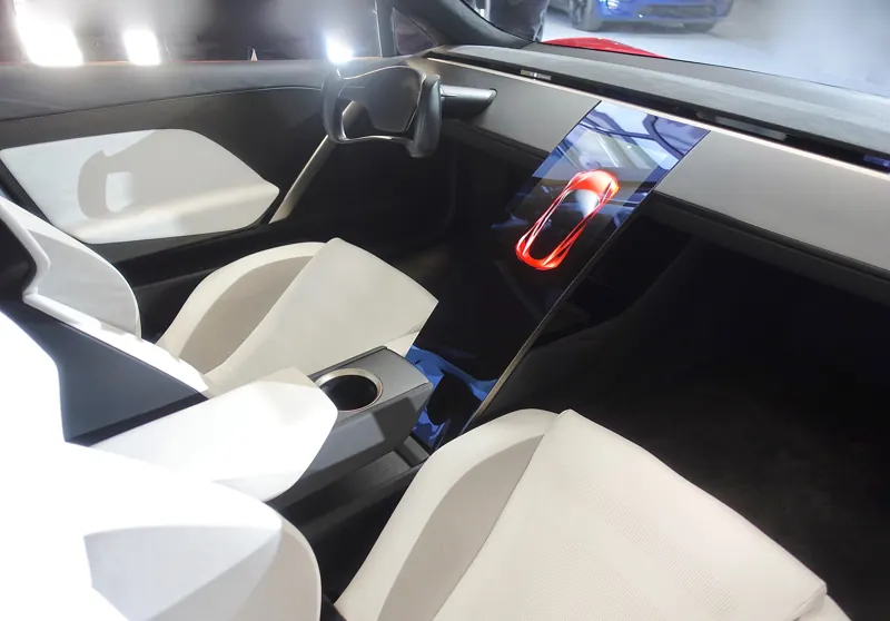 Interior of the Roadster prototype with white sport seats, a yoke-style steering wheel and a floating center screen