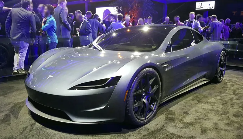 Silver second-generation Roadster prototype on display at a crowded evening event